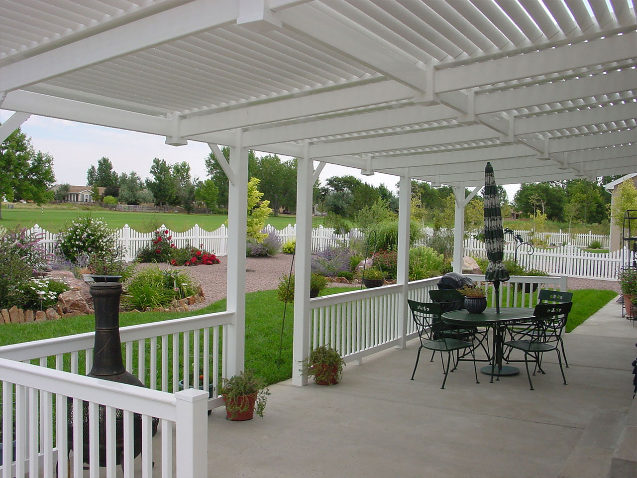 White vinyl pergola, patio railing and scalloped picket fence