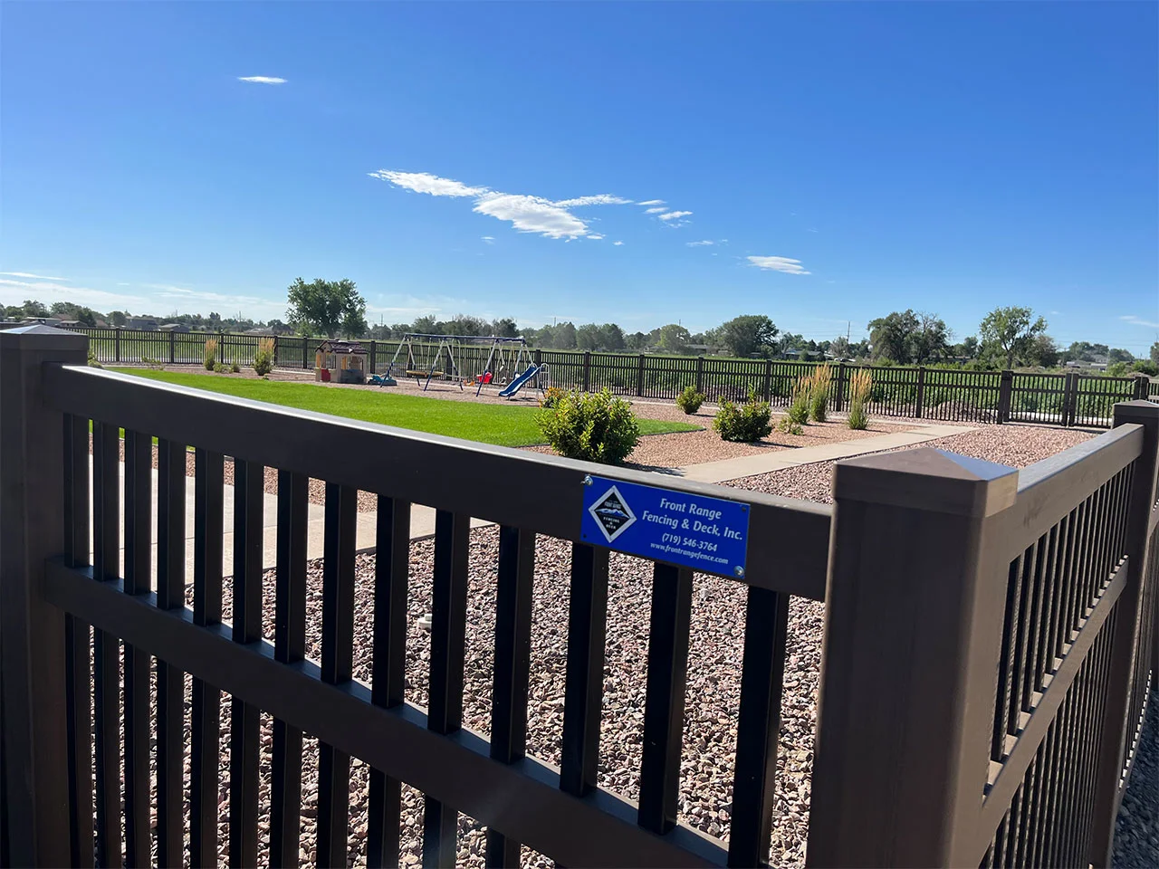 Vinyl black picket fence with brown railing and posts
